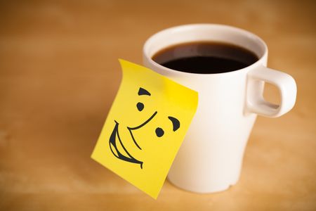 Drawn smiley face on a note sticked on a cup