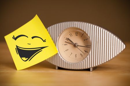 Drawn smiley face on a note sticked on alarm clock