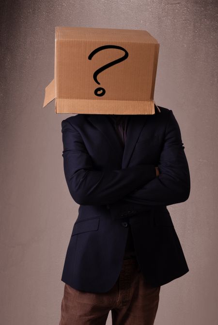 Young man standing and gesturing with a cardboard box on his head with question mark