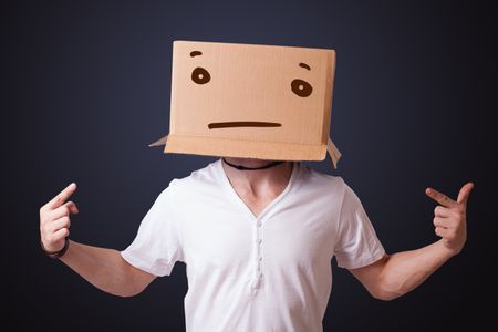 Young man standing and gesturing with a cardboard box on his head with straight face