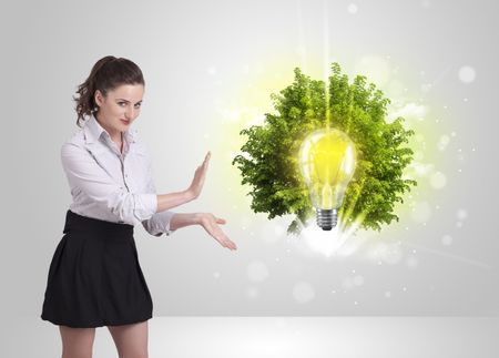 Young girl presenting idea light bulb with green tree concept