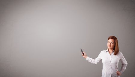 attractive young lady standing and holding a phone with copy space