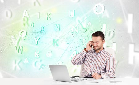 Business man at white desk with green word cloud