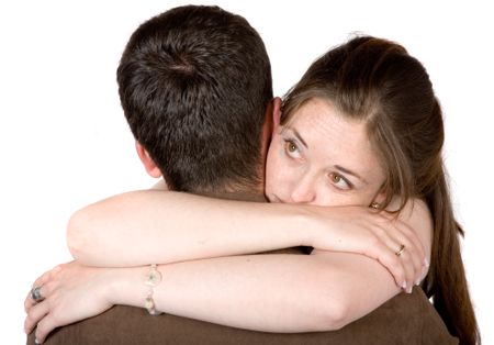 couple hugging while the woman is lokoing away in a pensive manner