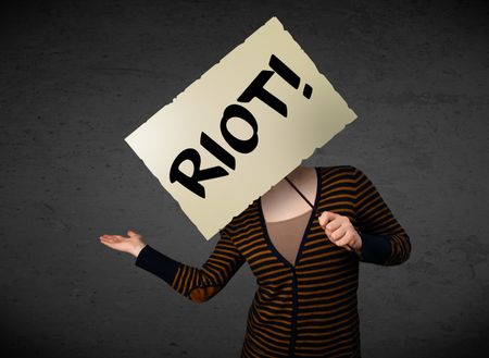 Young woman holding a demonstration board with riot sign in front of her head