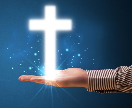 Young businessman holding a glowing cross in his hand