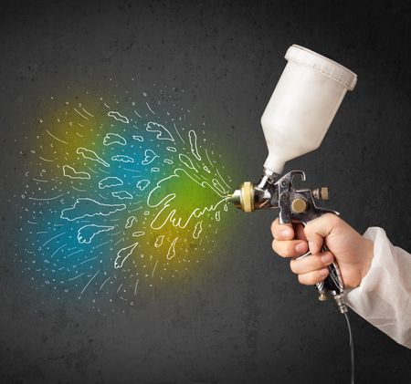 Worker with airbrush gun paints colorful lines and splashes concept