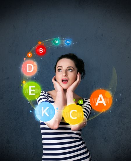 Thoughtful young woman with vitamin icons circulating around her head