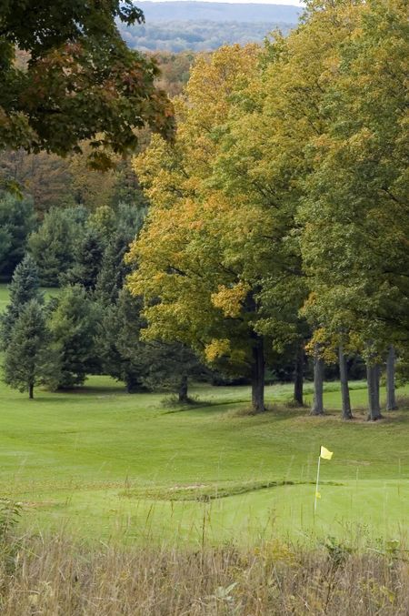 Ninth hole protected by bunker and trees on golf course in autumn
