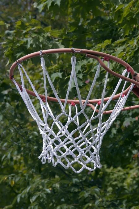 Basketball hoop and net with background of green tree leaves