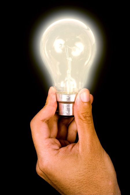 light bulb held by hand over a black background