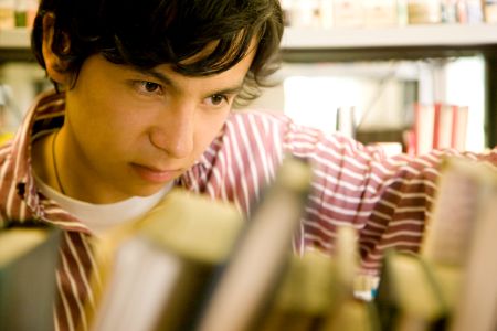 male university student at the library looking for a book