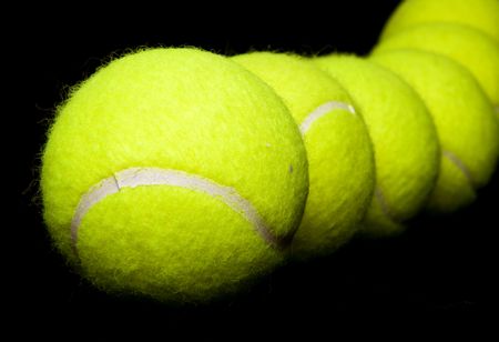 tennis balls in a row over a black background