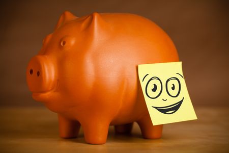 Drawn smiley face on a post-it note sticked on a piggy bank