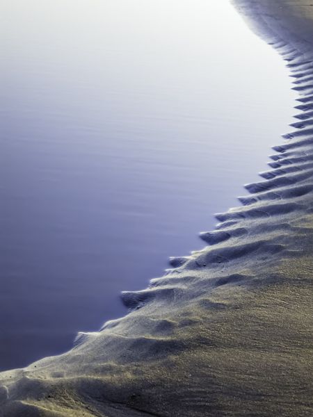 Abstract pattern created by ocean tide: Evening tidal pool with serrated edge in sand on Kalaloch Beach in the Pacific Northwest