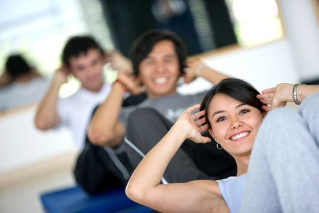 group of people at the gym smiling an doing abs exercises