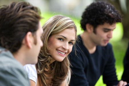 group of friends outdoors in a park smiling - focus on woman