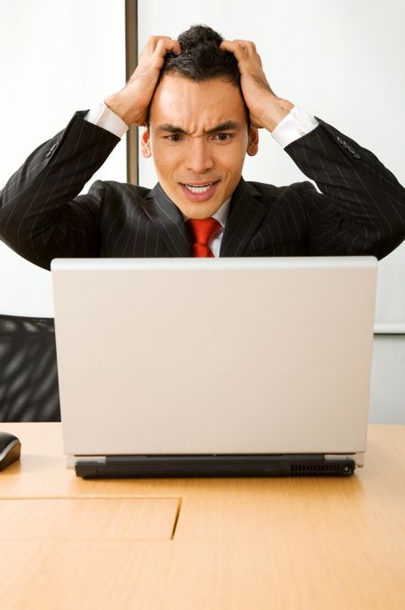 stressed business man in an office on a laptop computer