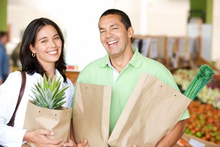 Beautiful couple smiling at a supermarket carrying shopping bags