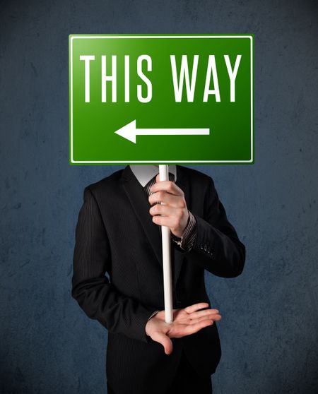 Businessman standing and holding a green direction sign in front of his head