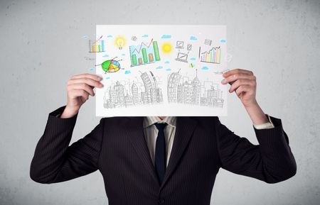 Businessman holding a paper in front of his head with charts and cityscape drawing