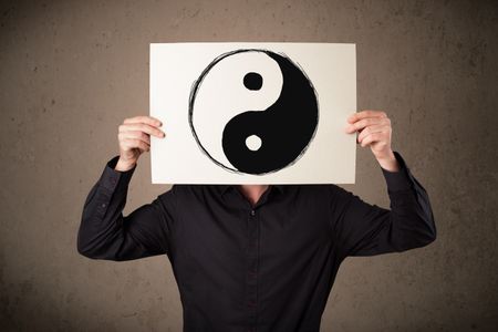 Businessman holding a paper with a yin-yang symbol on it in front of his head