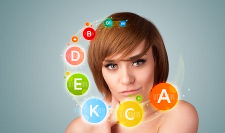 Pretty young girl with colorful vitamin icons and symbols on gradient background