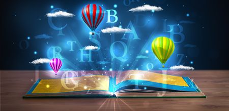 Open book with glowing fantasy abstract clouds and balloons on wood deck