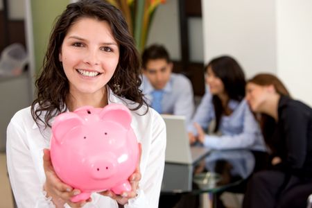 business woman showing her savings in a piggy bank at her office