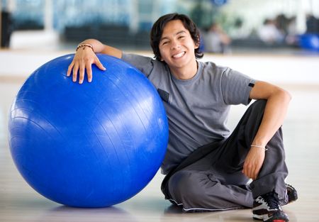 gym man doing pilates exercises on a blue ball