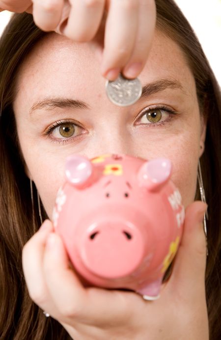 woman placing a coin inside a piggybank - focus is on eyes of the lady