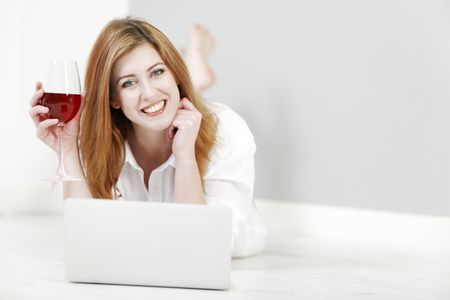 attractive-young-woman-working-home-laptop-208214233 Attractive young woman working from home on a laptop enjoying a glass of wine.