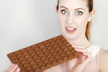 Attractive young woman enjoying a large chocolate bar.