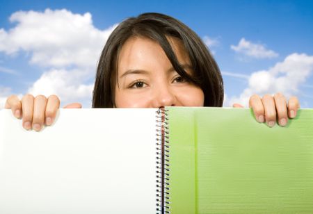 beautiful student looking over notebook with the sky in the background
