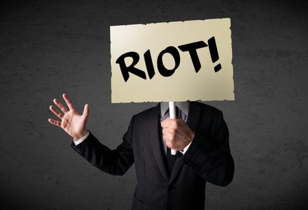 Businessman holding a demonstration board with riot sign in front of his head