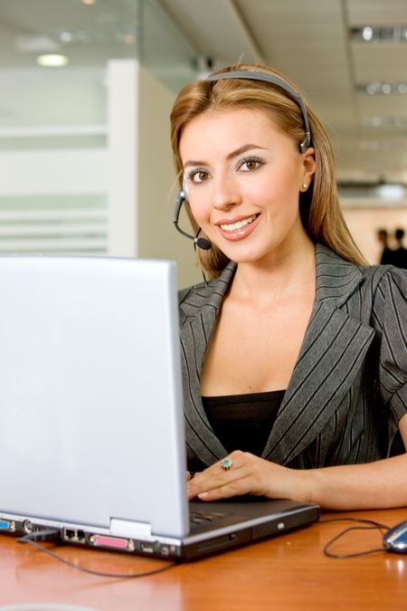 helpdesk woman on a laptop in an office smiling