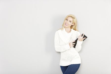 Beautiful young woman holding a tablet computer in her crossed arms