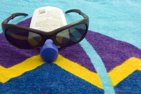 Sunglasses on a bottle of sunscreen on a beach towel