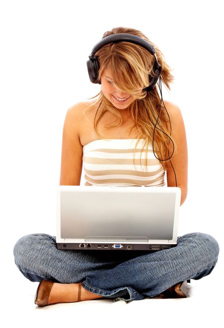 Casual student listening to music on the computer while studying isolated over a white background