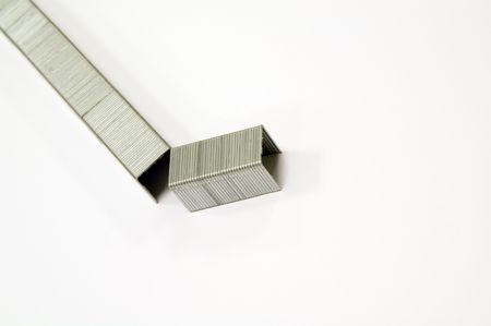 Row of staples, with breakaway section, on white background