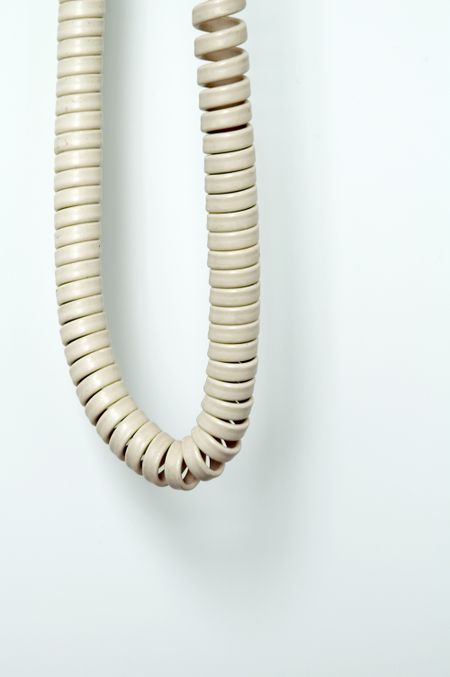 Telephone cord hanging in a loop by wall
