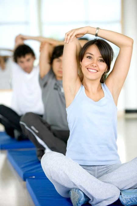 group of people at the gym smiling an doing stretching exercises