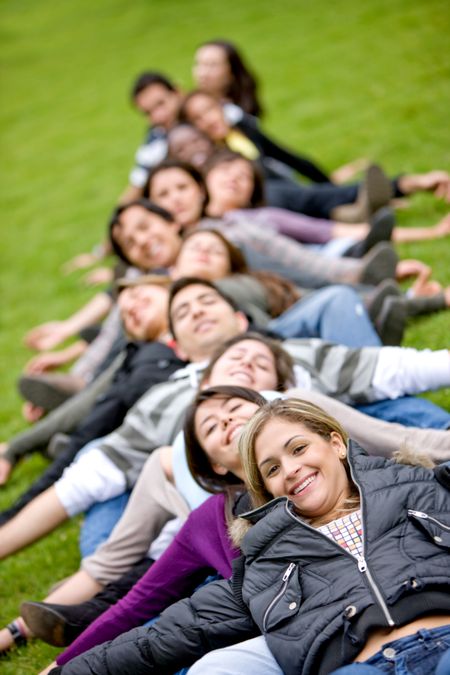 happy group of friends lying on the grass outdoors in a park