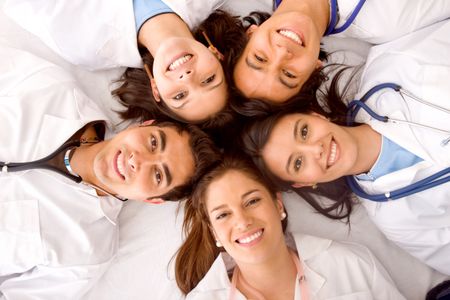happy group of doctors smiling with their heads together isolated over a White background