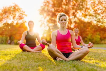 group of 3 women doing yoga in nature