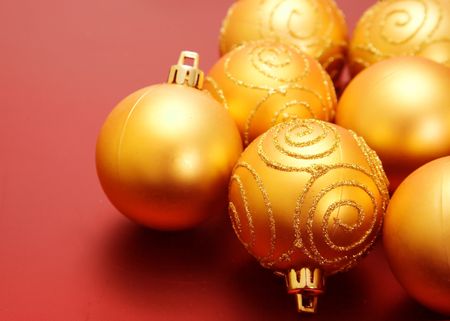 christmas golden baubles over a red background with space for writing