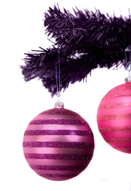 purple and pink christmas balls hanging from a dark coloured xmas tree