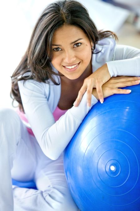beautiful woman portrait at the gym smiling leaning on a pilates ball