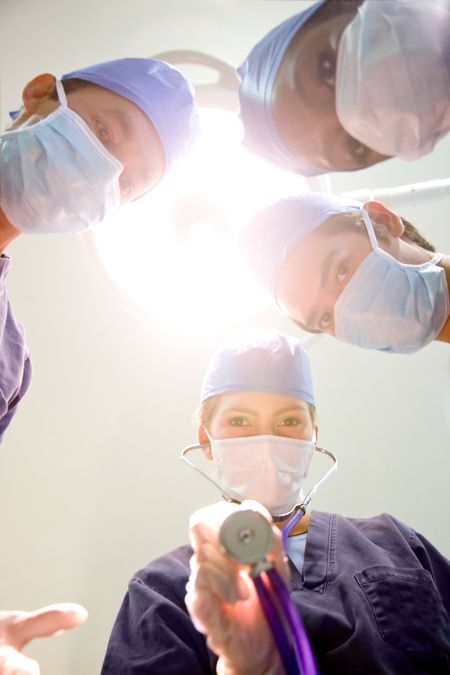 group of surgeon doctors in a hospital standing under a bright light