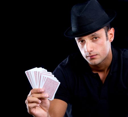 male magician holding cards in his hand - isolated over black